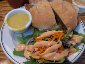 cajun seitan sandwich, "cheese" sauce, side salad with vegan thousand island